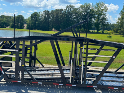 Rows of stacked rectangular and square American-sourced steel tubes and beams stretch into the background of a manufacturing facility, with a person visible in the distance.