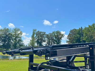 Rows of stacked rectangular and square American-sourced steel tubes and beams stretch into the background of a manufacturing facility, with a person visible in the distance.