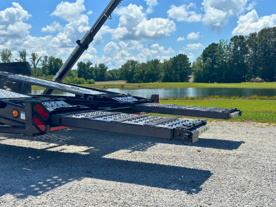 Rows of stacked rectangular and square American-sourced steel tubes and beams stretch into the background of a manufacturing facility, with a person visible in the distance.